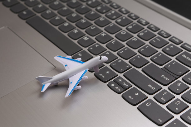 笔记本电脑键盘上的玩具飞机，旅行概念图片下载