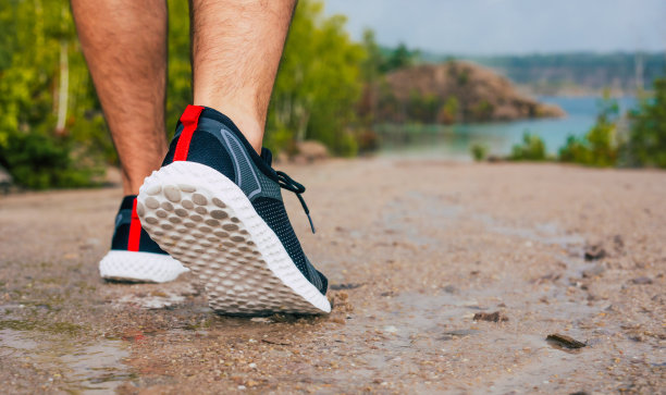 男运动鞋的特写照片，做运动，走或跑在山区的乡村道路上，靠近湖泊，健康和生活方式的概念。游客徒步旅行。图片下载