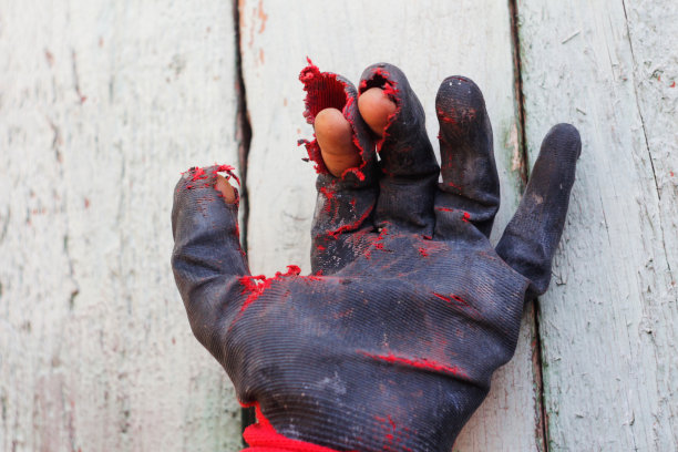 散焦时戴的手套又脏又漏。打开戴着工人手套的手掌，防止在操作过程中受伤，特写在灰色背景上。焦距不清图片下载