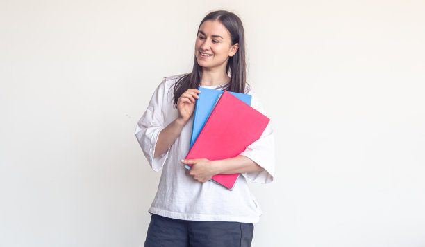 年轻女子拿着白色背景的彩色记事本，抄写。图片下载