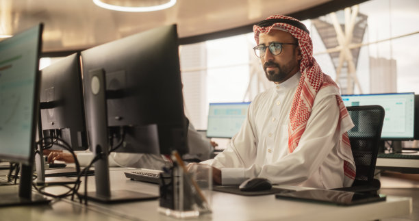 一个中东工程师在一个技术办公环境中使用台式电脑工作的肖像。阿拉伯软件开发人员研究解决技术任务的新思路图片下载