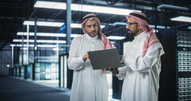 中东计算机工程师和网络安全专业人员在服务器机房工作，谈话，用笔记本电脑进行系统维护检查。专家在数据中心做数据库诊断图片下载