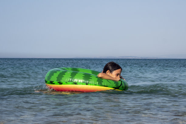 男孩在海里玩游泳圈。图片下载