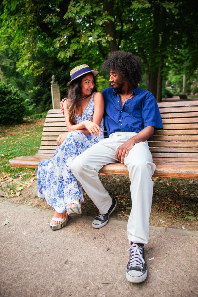 坐在长椅上交谈的多民族情侣竖版照片图片下载