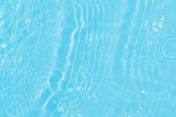 蓝蓝的水面上泛起涟漪。散焦模糊透明蓝色透明平静水面纹理与飞溅和气泡。水波与闪亮的图案纹理背景。图片下载