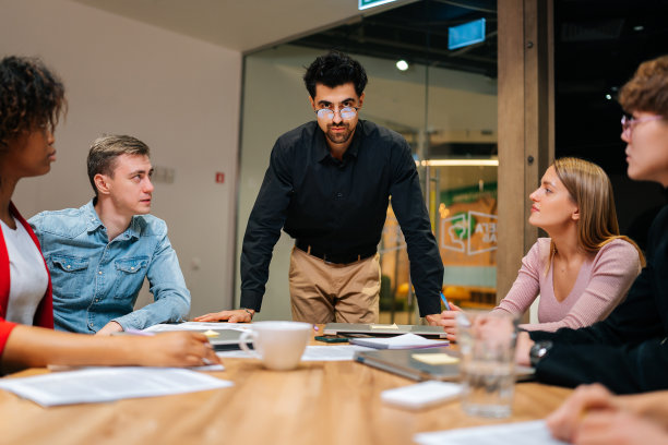 自信的男性商业团队领导站在多种族同事的包围下，看着镜头。多民族创业团队图片下载