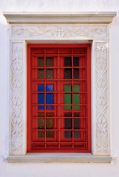 某个基督教教堂的旧窗户。彩色彩色玻璃，大理石雕刻与花卉动机和基督教十字架的装饰品。红色的框架。细节图片下载