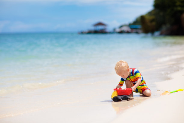 孩子们在热带海滩上玩耍。沙子和水的玩具。图片下载