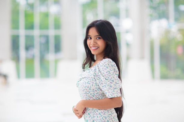 年轻的亚洲女人在室内。大窗口的女孩。图片下载