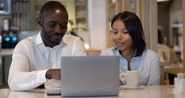 一对年轻的同事坐在咖啡馆里用笔记本电脑工作图片下载
