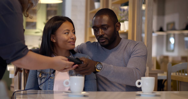 年轻夫妇在咖啡馆用信用卡付款图片下载