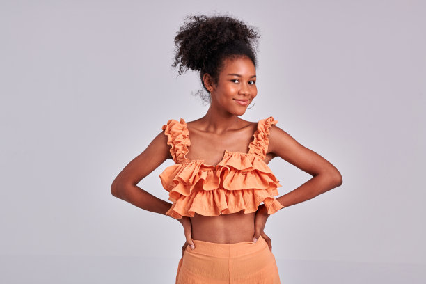 工作室魅力:黑人女孩穿着橙色衬衫漂亮地摆姿势图片下载