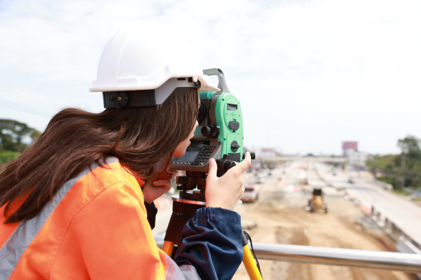 现场女工程师在道路施工期间操作她的仪器。施工人员在施工现场使用全站测速仪进行新道路放线图片下载