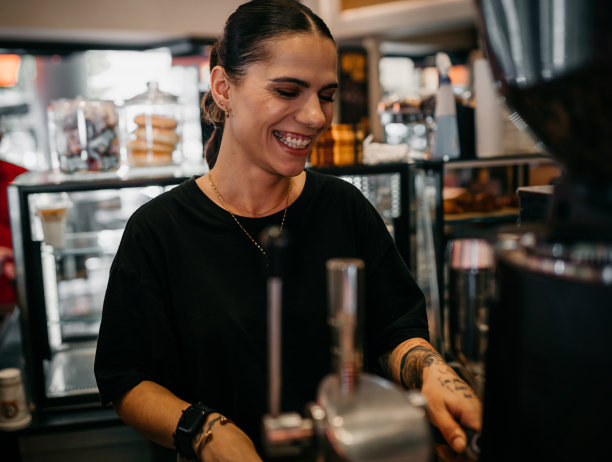 微笑的咖啡师用咖啡机煮热牛奶图片下载