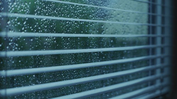 窗帘后面的窗户上有雨滴。图片下载