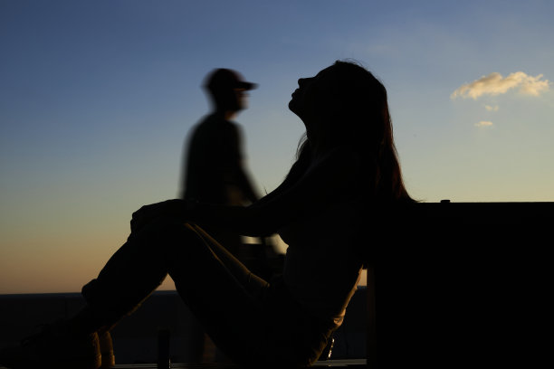 蓝天下，一位年轻女士在公园放松的剪影图片下载