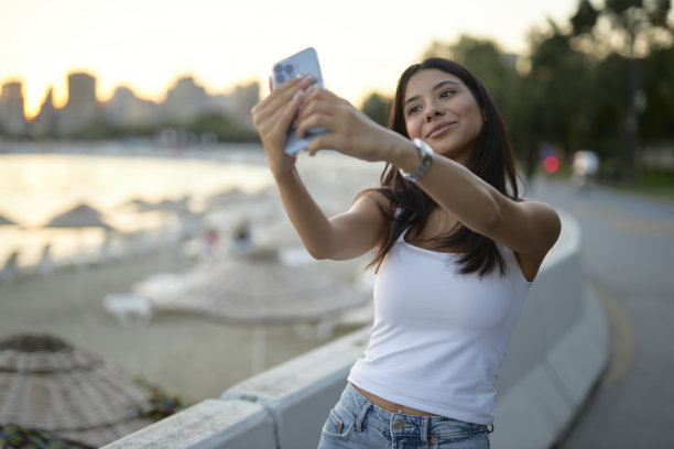 年轻的黑发女郎在海滨公园自拍图片下载