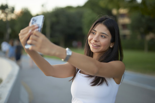 年轻的黑发女郎在海滨公园自拍图片下载