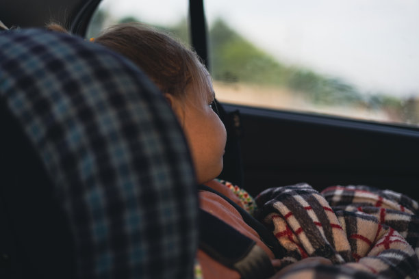 一个可爱的女孩坐在汽车座椅上，因为长途旅行而疲惫不堪，她望着窗外。夏天开车旅行时，孩子要安全地坐在儿童座椅上。日落时分，孩子坐在汽车座椅上。图片下载