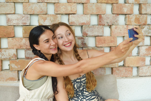 乌克兰女子(黑发)和俄罗斯女子(金发)梳着辫子摆姿势自拍图片下载