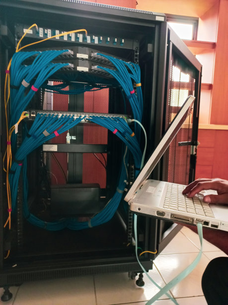 网络技术人员使用控制台电缆和以太网跳线设置和配置路由器交换机。图片下载