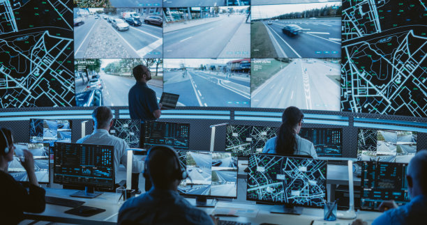 男软件工程师在一个现代化的监控办公室里，在一个大屏幕旁边的笔记本电脑上工作，现场监控着交通状况。监控室与大数据工程师在电脑上工作图片下载