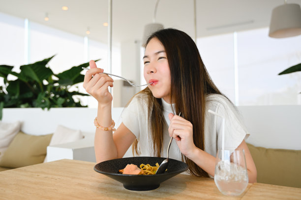 一个女人爱吃，拿着一盘食物，对着镜头微笑，享受她的食物，而不用担心超重或肥胖。这张照片质量很好。图片下载