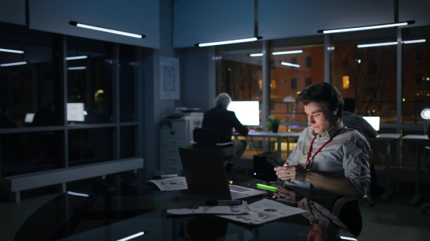 在现代办公室工作到很晚的公司经理用手机聊天图片下载