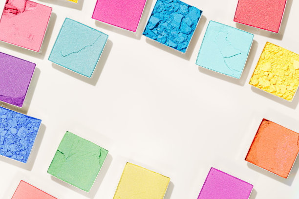 色彩鲜艳的眼影彩妆盘洋红色，红色，蓝色，黄色在米色的背景。女性化妆品及美容产品，亮丽眼影，美学创意框，复制空间图片下载