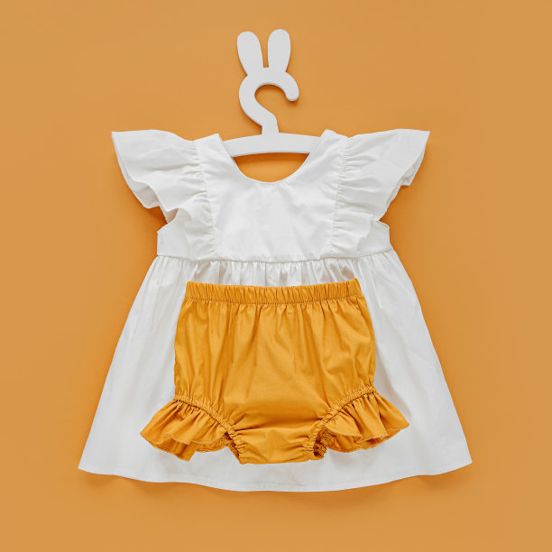 白色连衣裙，橙色短裤挂在可爱的挂钩上，还有兔子耳朵。一套婴儿服装和配件的春天或夏天。时尚的孩子的衣服。平铺，俯视图图片下载