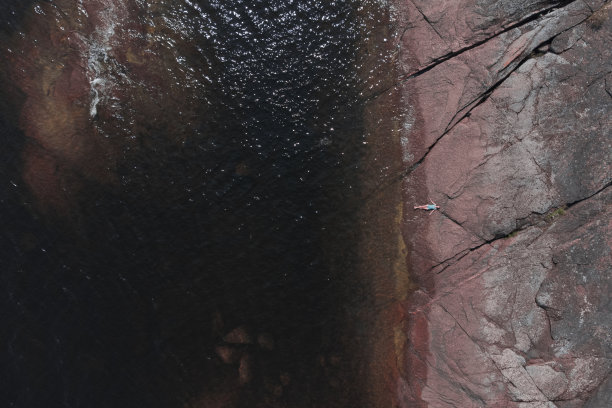 女人躺在花岗岩的海岸上图片下载