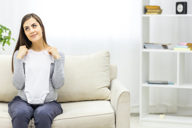 孕妇抱着小孩小衣服的照片。图片下载