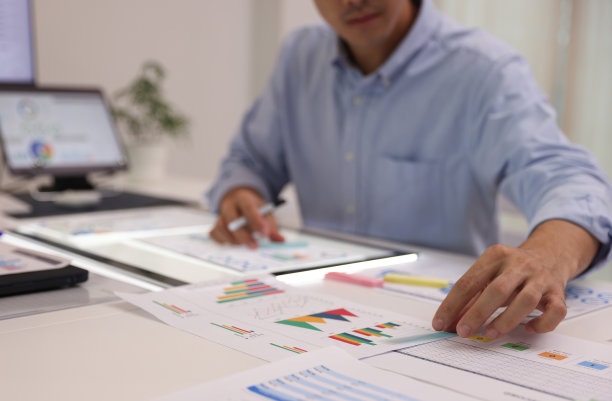 近景边年轻的商人在办公室工作，就多份报告进行介绍。图片下载