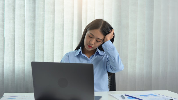 坐着工作的亚洲女性头痛。图片下载