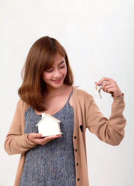 穿着休闲服的亚洲妇女手持白色背景的房屋模型图片下载