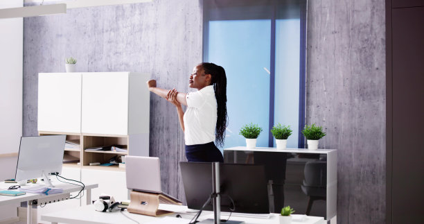 手臂伸展运动站在书桌附近图片下载