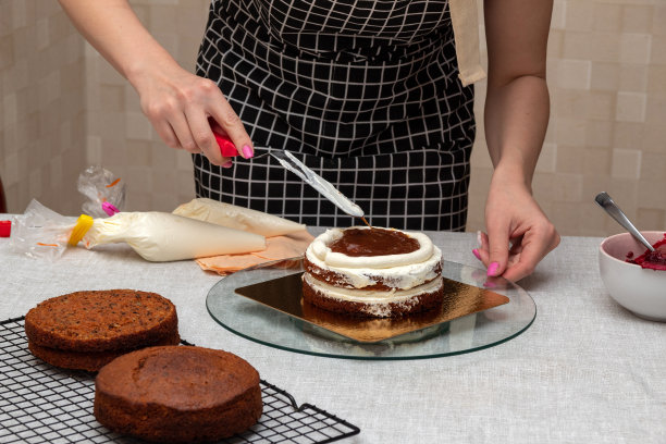女人用厨房抹刀抹平蛋糕里的焦糖。有选择性的重点。图片为食品，糖果商的文章。图片下载