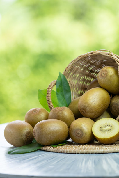 猕猴桃在木篮子在模糊绿色背景，黄色猕猴桃水果或中国醋栗在绿色自然模糊背景图片下载