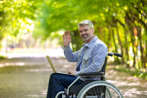 轮椅上的人使用笔记本电脑进行在线工作，残疾自由职业者从事远程项目图片下载