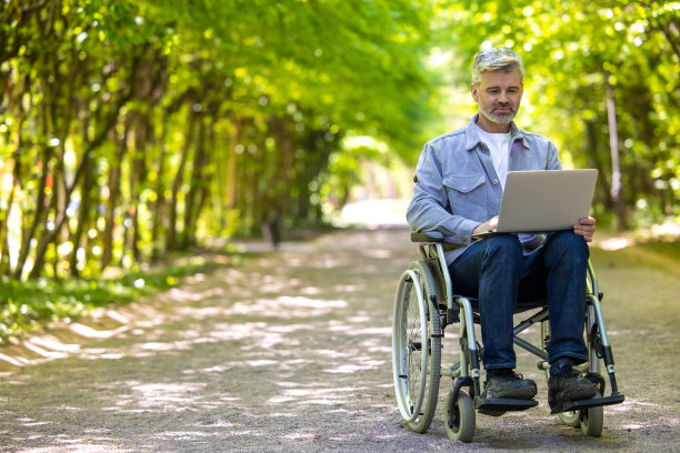 轮椅上的人使用笔记本电脑进行在线工作，残疾自由职业者从事远程项目图片下载