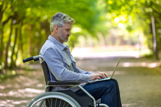 白发苍苍的残疾自由职业者坐在轮椅上在线工作。图片下载