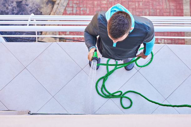 白人成年大胡子男子用水管清洗门、阳台、窗户，上图图片下载