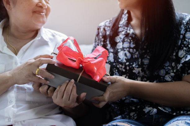 有爱心的年轻成年女性在家里祝贺激动的老母亲的生日纪念日。图片下载