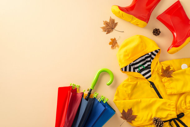 功能时尚的儿童防水服装。在米色背景上拍一张彩色胶靴、雨衣和雨伞的自上而下的照片，留出文字或广告位置图片下载