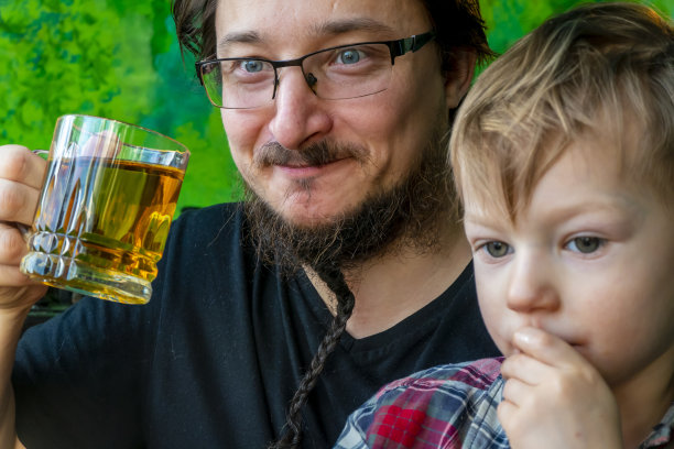 早安家庭幸福理念。父子俩在漆得像森林一样的厨房里喝茶。爸爸和儿子玩得很开心图片下载