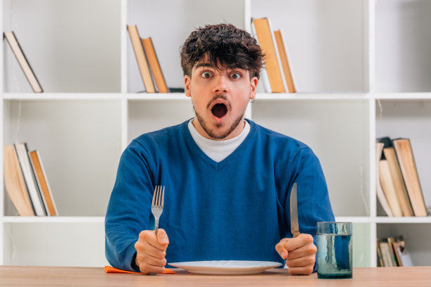 大学生在饭厅里坐在餐桌旁惊讶不已图片下载