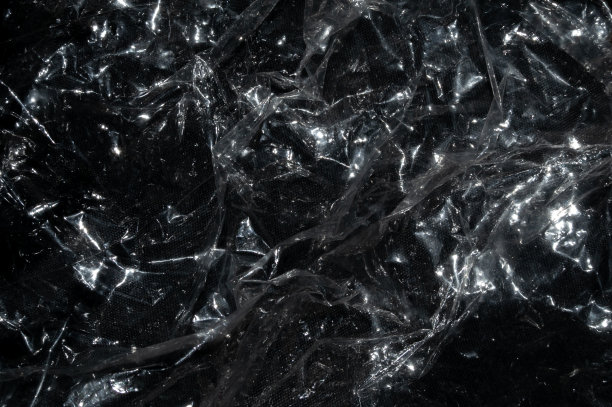 黑色背景上皱巴巴的塑料图片下载