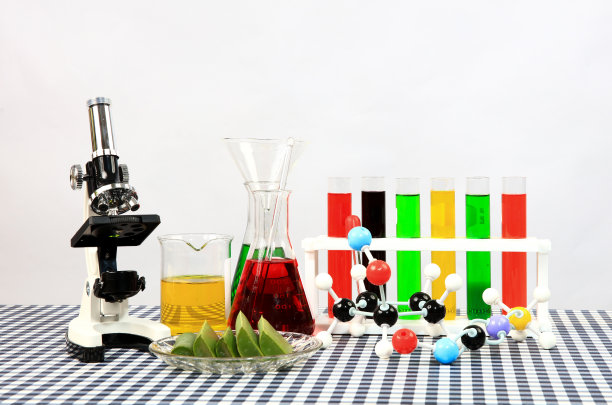 教育实验室，一套科学试验用玻璃，包括试管、贝格玻璃、装有彩色化学溶液的锥形烧瓶和白色背景桌子上的显微镜图片下载