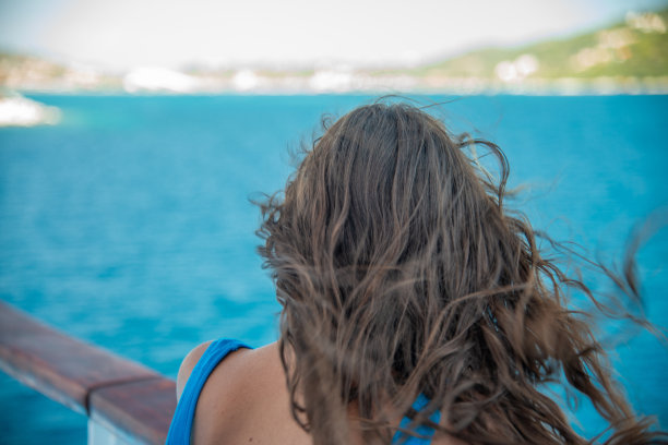一个美丽的女孩在夏天看着海岸线的背影图片下载