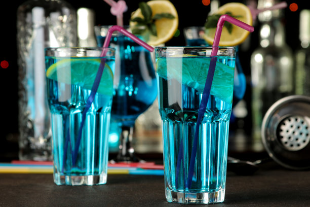 在酒吧里，棕色的桌子上，蓝色的鸡尾酒杯里放着柠檬和薄荷。酒吧配件。图片下载